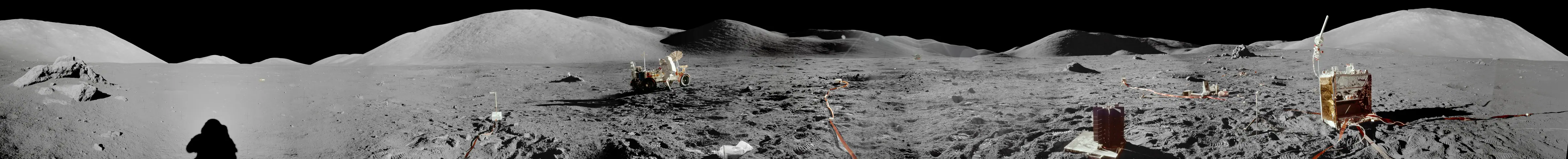 阿波罗 17 号 Taurus-Littrow 山谷着陆点全景：左侧可见宇航员影子与月面岩石，中央为月球车 LRV 与远山地平线，右侧为 ALSEP 科学仪器组。